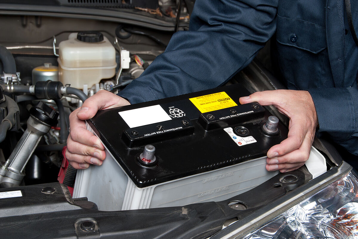 Jahreszeiten Check-Ups A car mechanic replaces a battery.